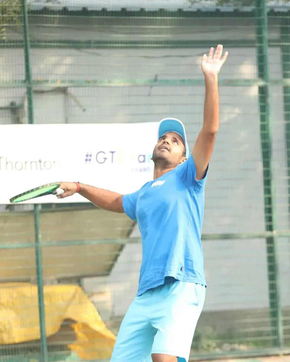A player in blue reaches up for a serve