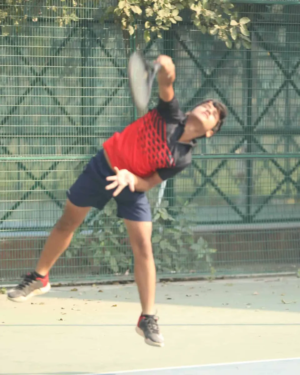 A player in red leaps into a serve