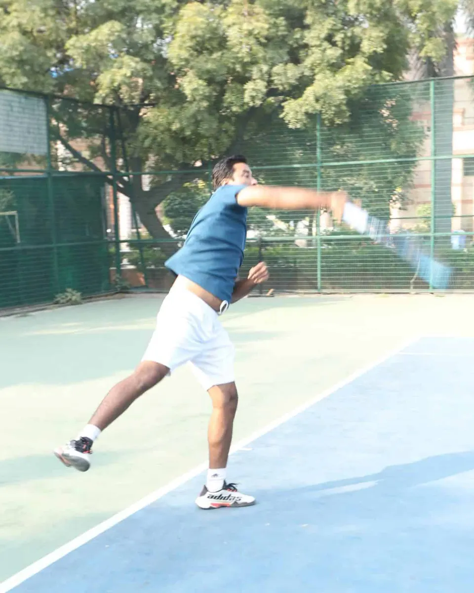 A player serves on a blue hard court