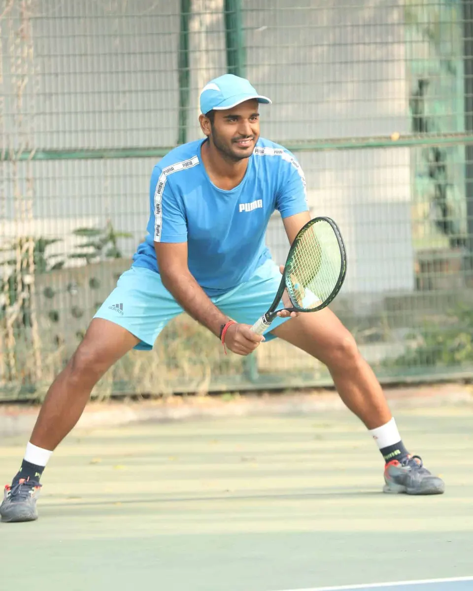 A tennis player in blue ready to receive at a historical RGT tournament